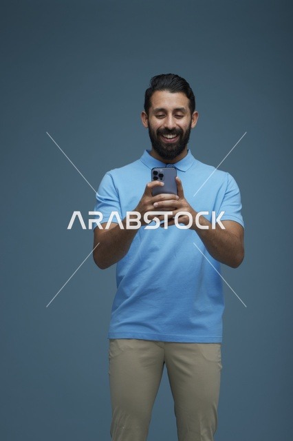 شاب سعودي يستخدم الهاتف الذكي بملابس كاجوال