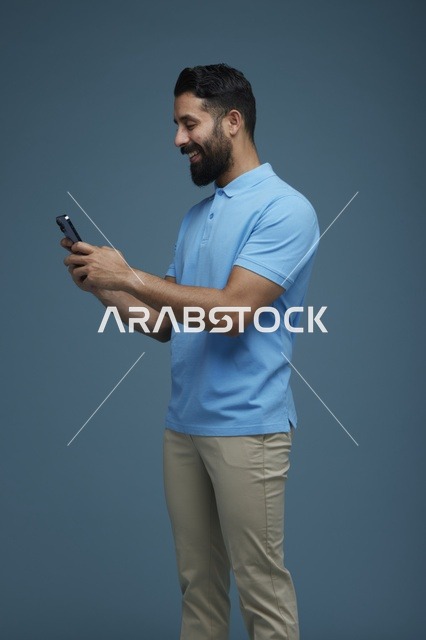 شاب سعودي يستخدم الهاتف الذكي بملابس كاجوال زرقاء