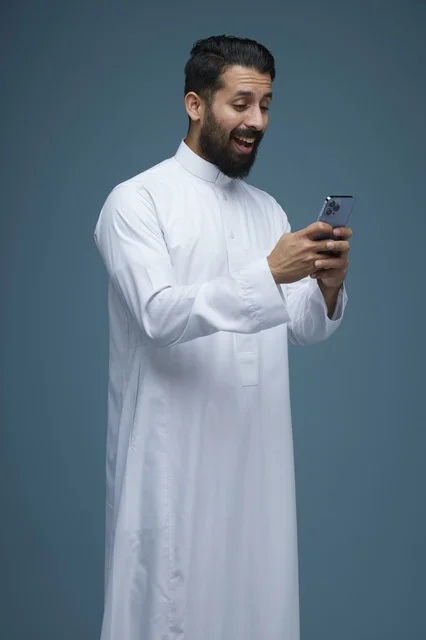 Saudi Man in Traditional Thobe Using Smartphone