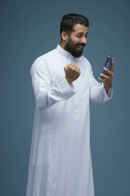 رجل سعودي يحتفل بالنجاح باستخدام الهاتف الذكي