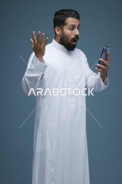 رجل سعودي بالثوب التقليدي مصدوم من الهاتف