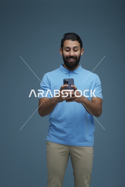 شاب سعودي يستخدم الهاتف الذكي بملابس كاجوال زرقاء