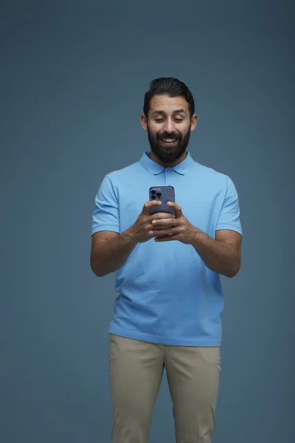 Saudi Man Using Smartphone in Casual Blue Polo Shirt