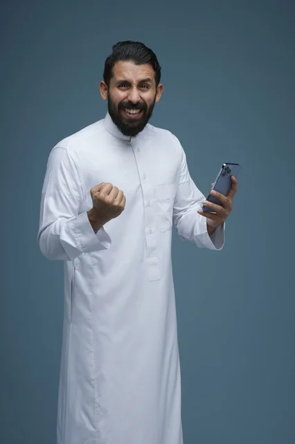 Excited Saudi Man in Thobe Using Smartphone
