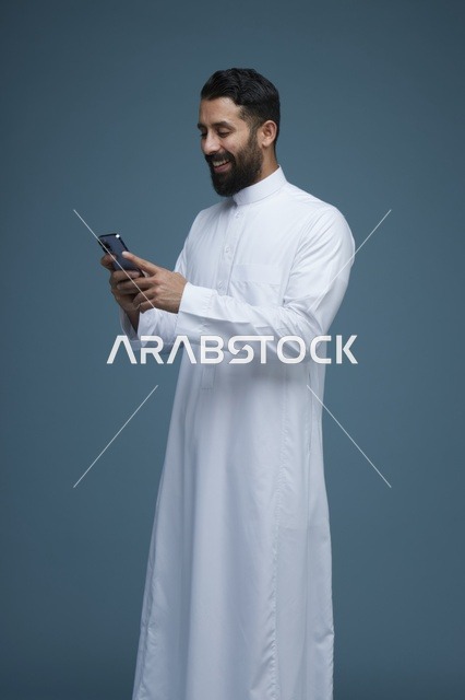 رجل سعودي يستخدم الهاتف الذكي بالثوب التقليدي