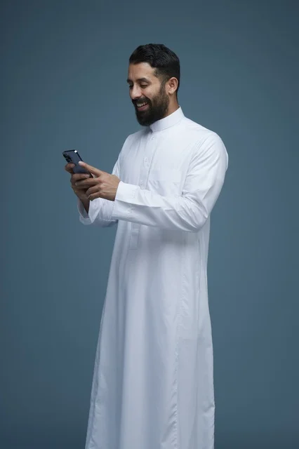 رجل سعودي يستخدم الهاتف الذكي بالثوب التقليدي