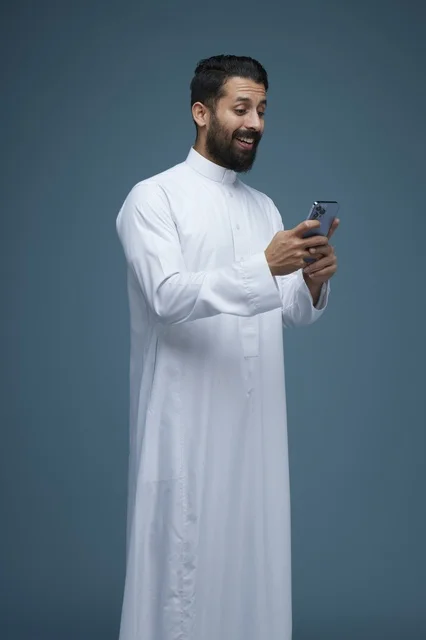 رجل سعودي بالثوب التقليدي يستخدم الهاتف الذكي استوديو
