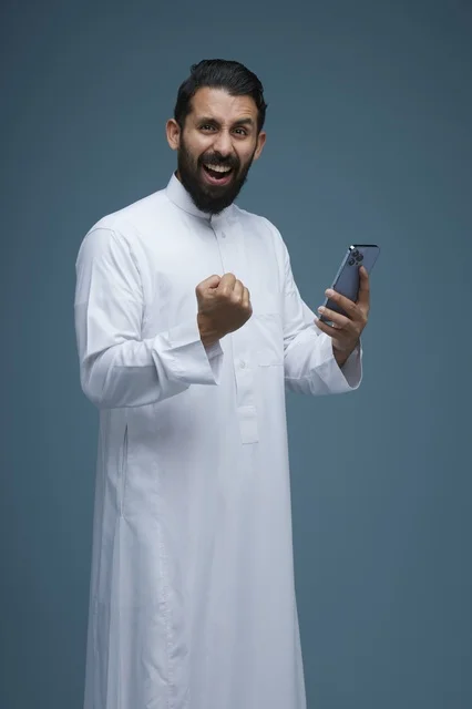 Excited Saudi Man in Thobe Using Smartphone Success
