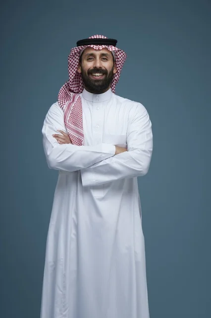 رجل سعودي بالزي التقليدي يبتسم في استوديو بورتريه