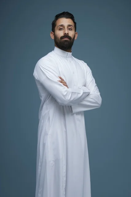 رجل سعودي بالثوب الأبيض في استوديو بخلفية زرقاء
