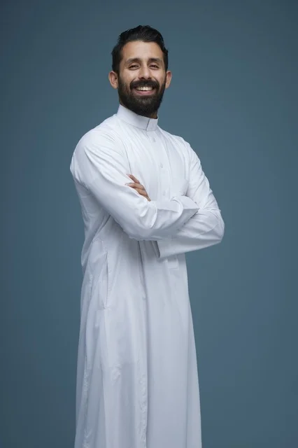رجل سعودي يبتسم بالثوب الأبيض على خلفية زرقاء