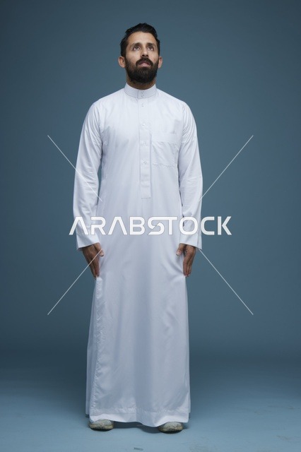 رجل سعودي بالثوب الأبيض ينظر للأعلى لقطة استوديو كاملة