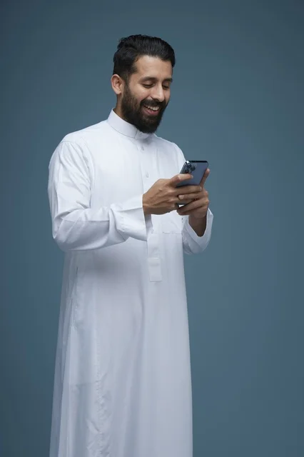 رجل سعودي يستخدم الهاتف الذكي بالثوب التقليدي