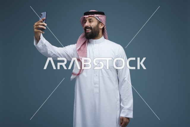 رجل سعودي يلتقط صورة سيلفي بالهاتف الذكي بالثوب