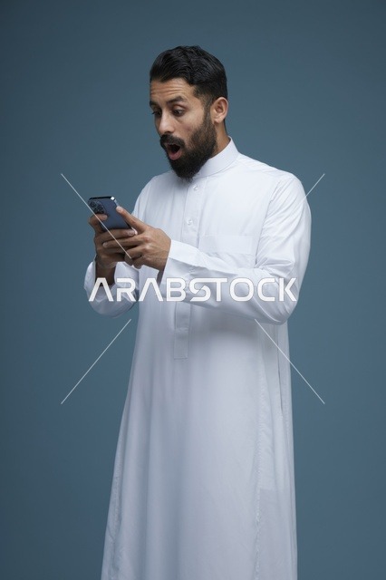 رجل سعودي مندهش يستخدم الهاتف الذكي بالثوب التقليدي