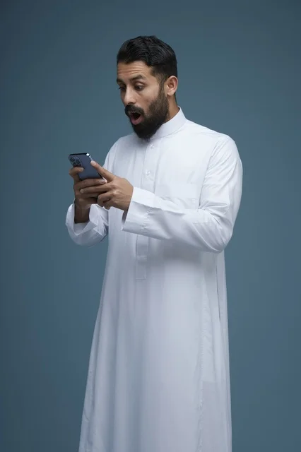 رجل سعودي مندهش يستخدم الهاتف الذكي بالثوب التقليدي
