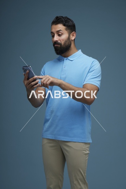 رجل سعودي يستخدم الهاتف الذكي بملابس كاجوال