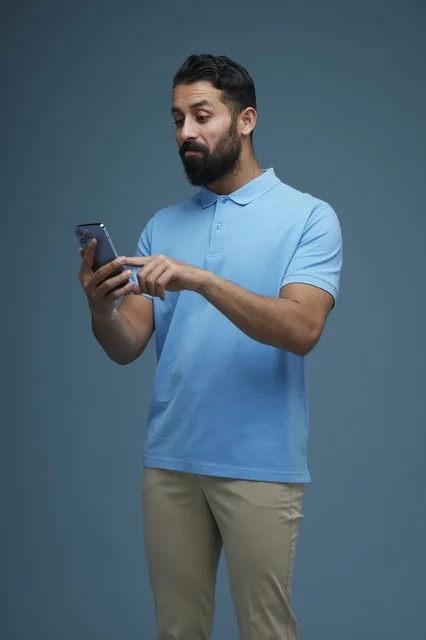 Saudi Man Using Smartphone in Casual Blue Polo