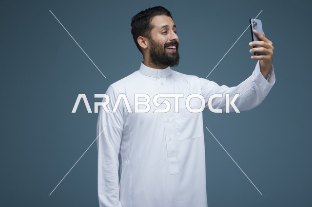 رجل سعودي بالثوب الأبيض يلتقط صورة سيلفي بالجوال