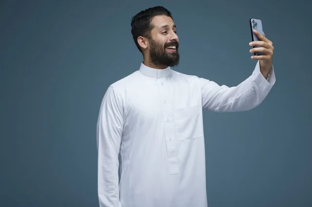 رجل سعودي بالثوب الأبيض يلتقط صورة سيلفي بالجوال