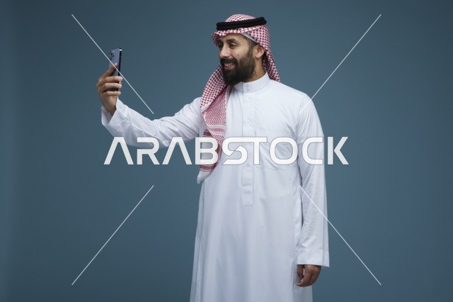 رجل سعودي يلتقط صورة سيلفي بالهاتف الذكي في الاستوديو