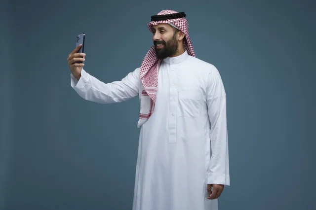 رجل سعودي يلتقط صورة سيلفي بالهاتف الذكي في الاستوديو