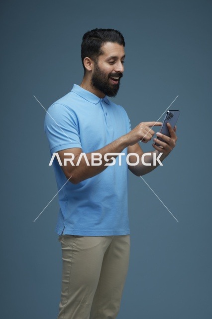 رجل سعودي يستخدم الهاتف الذكي بملابس كاجوال