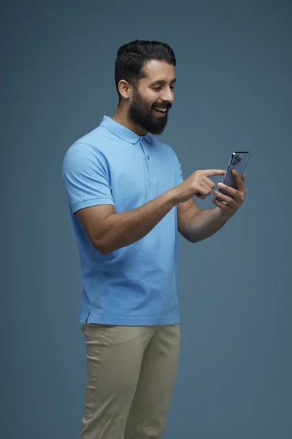Saudi Man Using Smartphone Wearing Casual Blue Polo Shirt