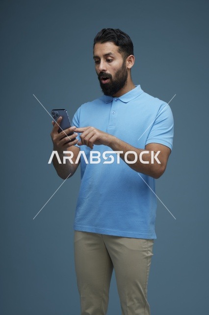 رجل سعودي يستخدم الهاتف الذكي بتعبير مندهش