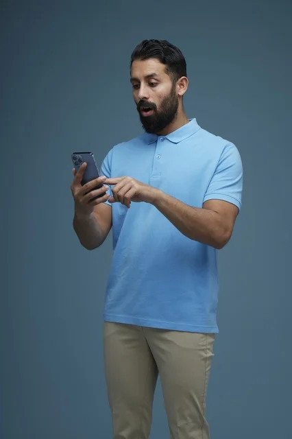 Saudi Man with Smartphone Surprised Expression Casual Wear