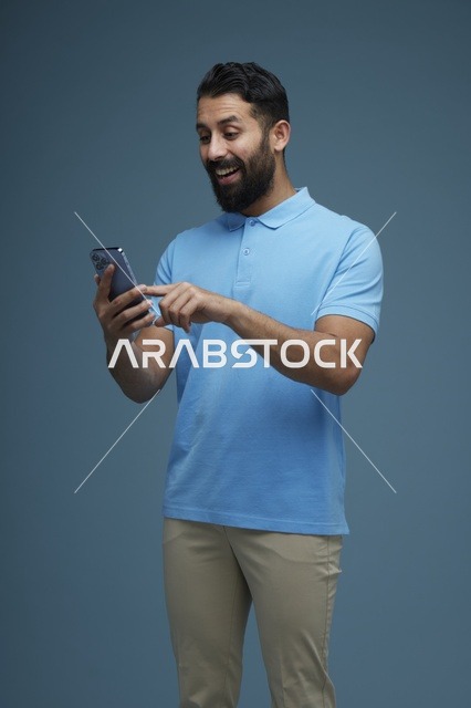 رجل سعودي يستخدم الهاتف الذكي بملابس كاجوال