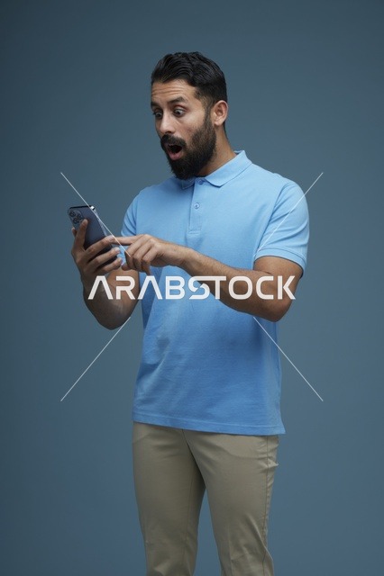 رجل سعودي مصدوم يستخدم الهاتف الذكي بملابس كاجوال