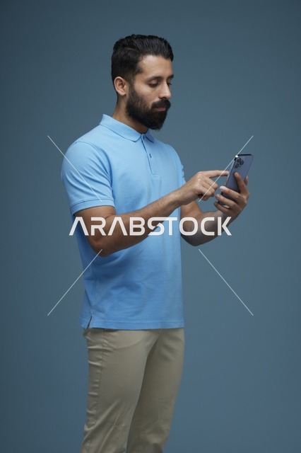 رجل سعودي يستخدم الهاتف الذكي بملابس كاجوال