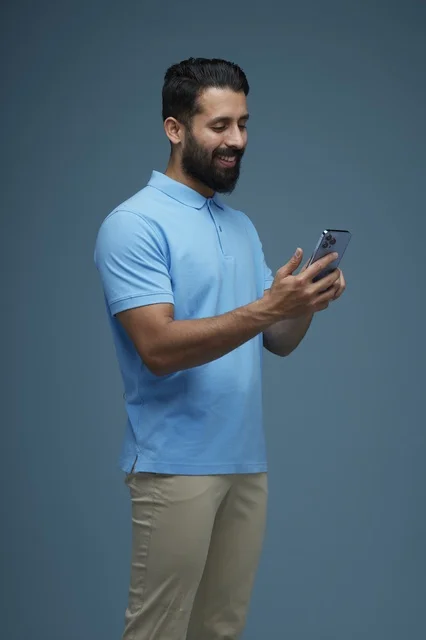 Saudi Man Using Smartphone on Blue Background