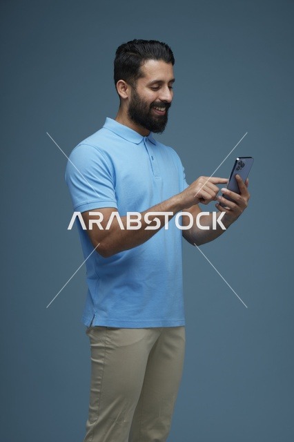 رجل سعودي يستخدم الهاتف الذكي بملابس كاجوال
