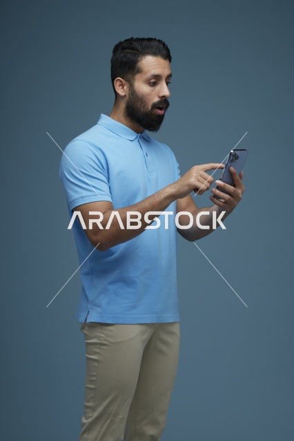 رجل سعودي يستخدم الهاتف الذكي بتعبيرات وجه مصدومة ومندهشة