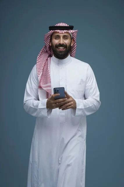 Saudi Man in Traditional Thobe Using Smartphone Studio Shot