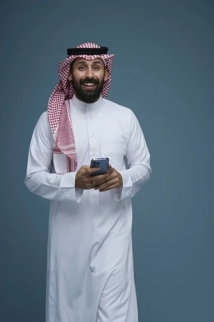 Saudi Man in Traditional Dress Using Smartphone in Studio