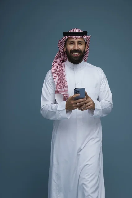رجل سعودي يستخدم الهاتف الذكي بالزي التقليدي في الاستوديو