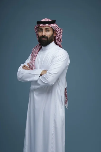 رجل سعودي يرتدي الزي السعودي التقليدي أمام خلفية زرقاء