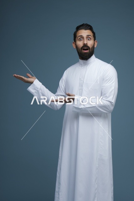 رجل سعودي مندهش يرتدي الثوب ويشير بيديه نحو الجانب