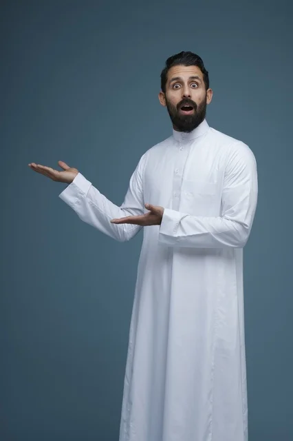 رجل سعودي مندهش يرتدي الثوب ويشير بيديه نحو الجانب