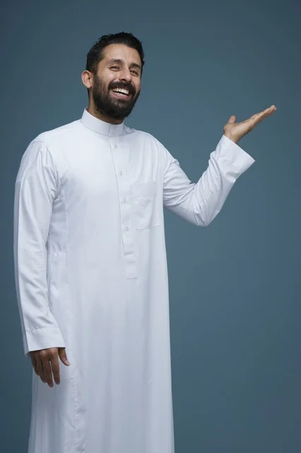 رجل سعودي بالثوب الأبيض يشير بيديه أمام خلفية زرقاء