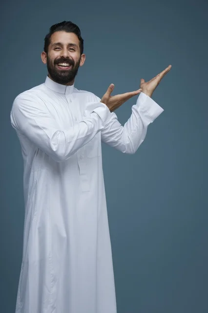 رجل سعودي بالثوب الأبيض يشير بيديه خلفية زرقاء