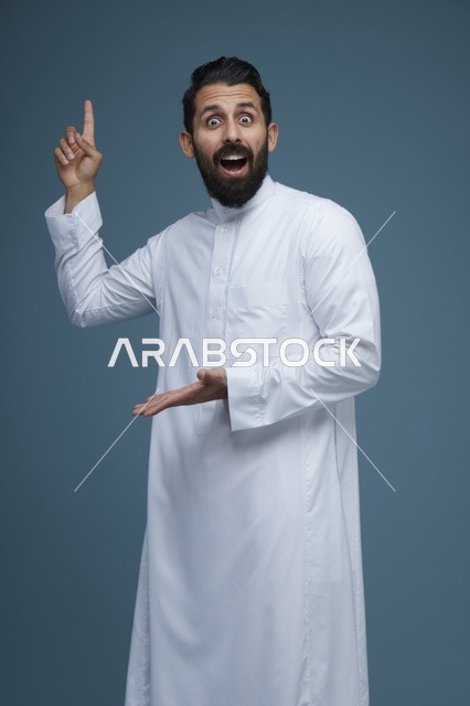 رجل سعودي بالثوب الأبيض يشير للأعلى بتعابير مندهشة