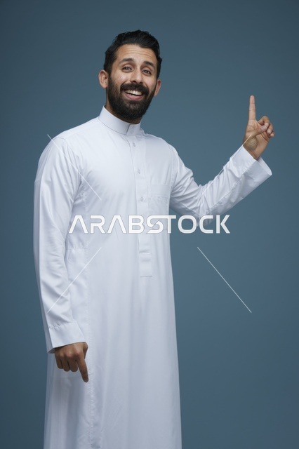 رجل سعودي بالثوب التقليدي يشير للأعلى والأسفل بوجه مبتسم