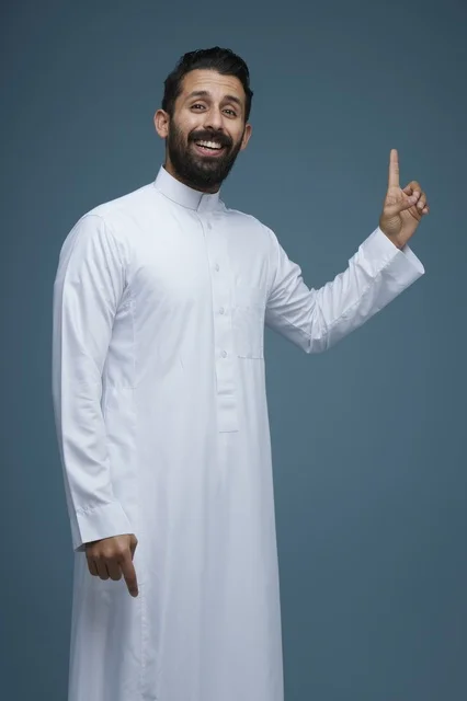 رجل سعودي بالثوب التقليدي يشير للأعلى والأسفل بوجه مبتسم