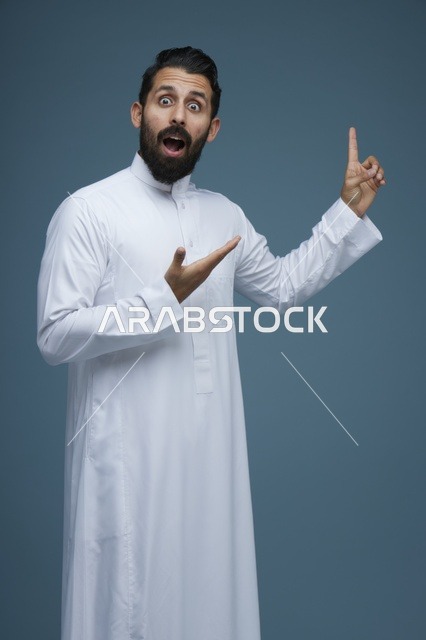 رجل سعودي مندهش يشير للأعلى بالثوب الأبيض التقليدي