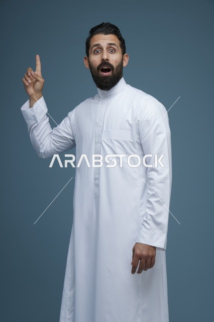 رجل سعودي بالثوب يشير للأعلى بتعبير مفاجئ