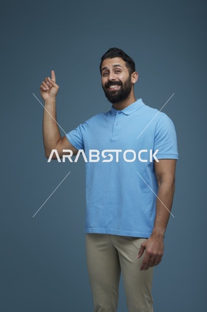 رجل سعودي يبتسم ويشير للأعلى خلفية زرقاء